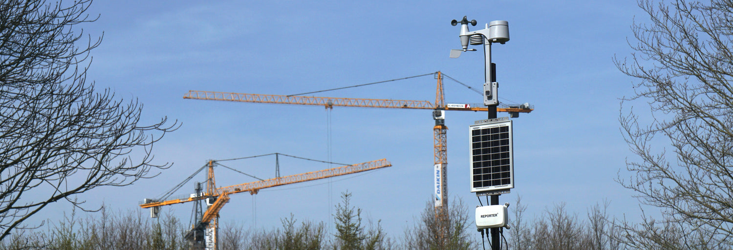 Reporter with solar panel in front of cranes