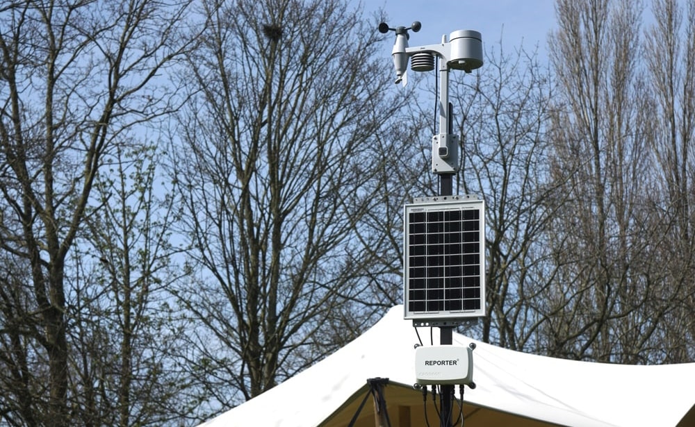Reporter with weather station next to a festival tent