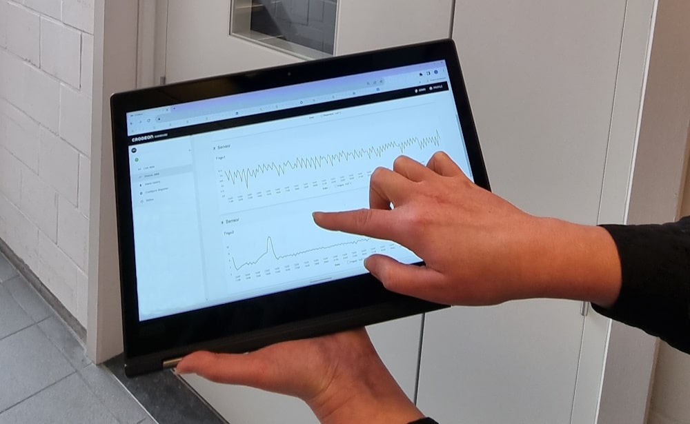 A person holding a tablet to show temperature measurements on the Crodeon Dashboard